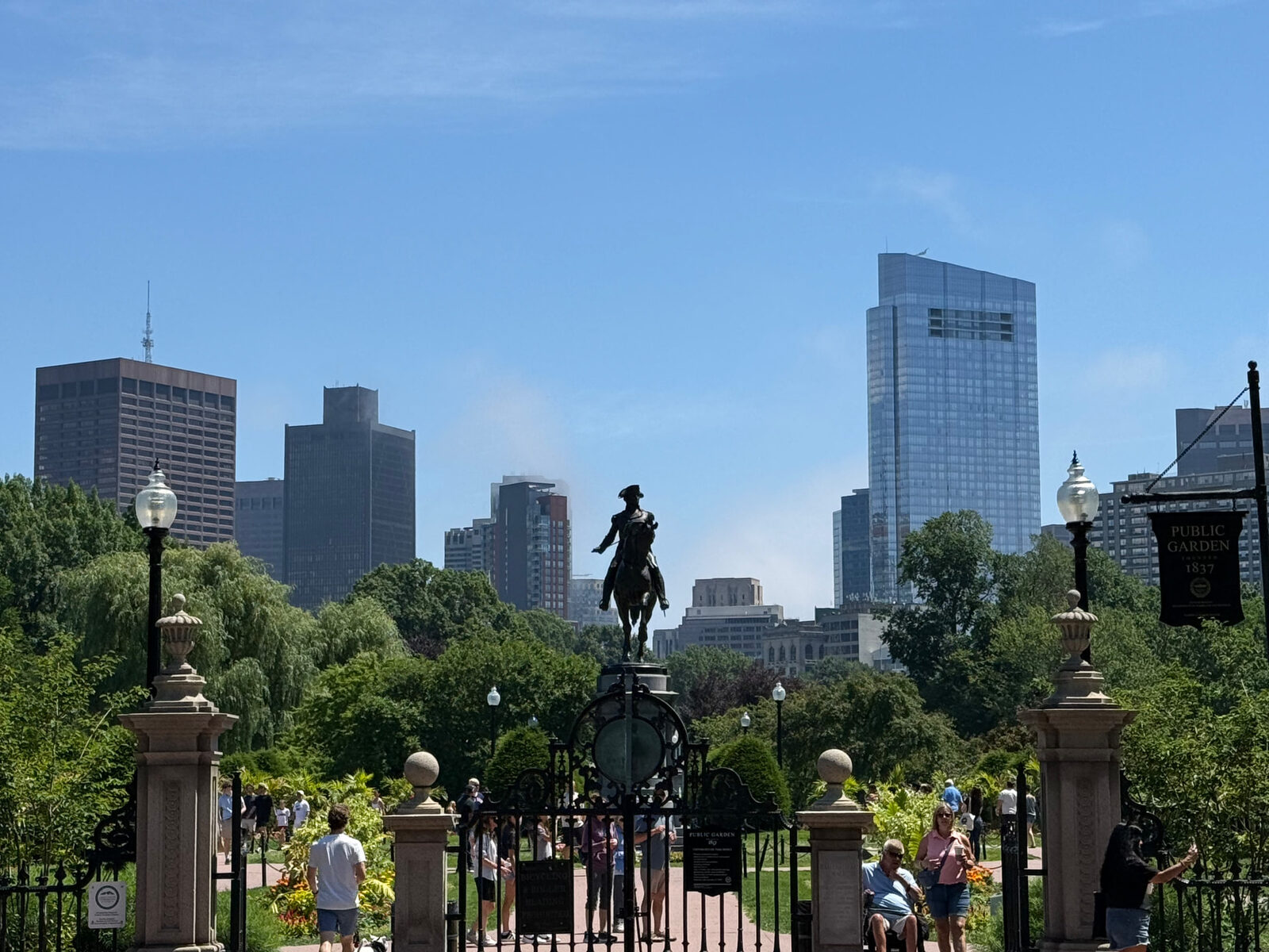 Boston skyline above the Public Garden gates and George Washington statue